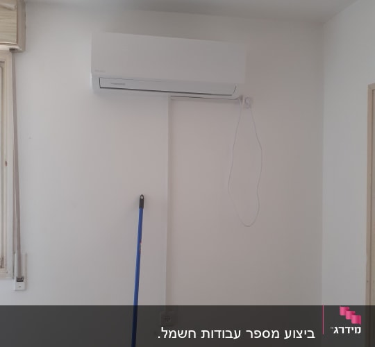 מזגן מותקן על קיר עם חוט חשמל חשוף